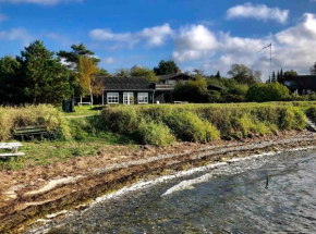 Sort sommerhus i æbleskov første række til havet